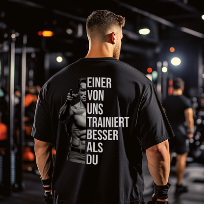 EINER VON UNS TRAINIERT BESSER ALS DU Unisex Oversized Shirt (Backprint)